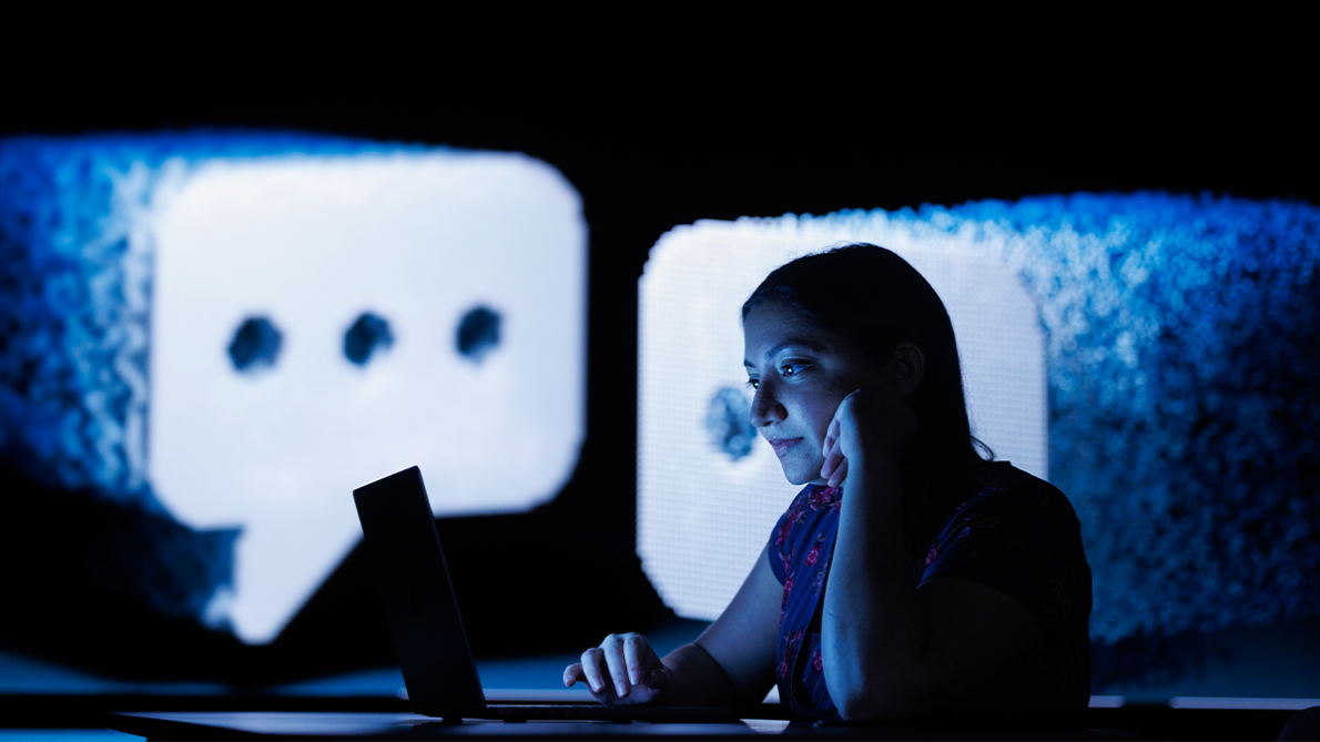 Woman in a darkened room looking at her laptop