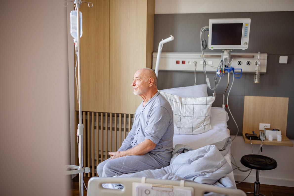 older patient staring while sitting on hospital bed