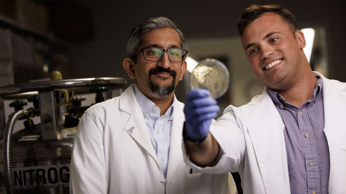 Sudarshan Rajagopal, MD, PhD and Preston Anderson examine a glass slide together.