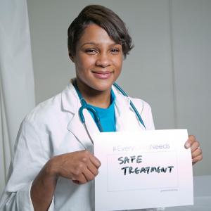 Dr. Kanecia Zimmerman holding a sign that say "Safe Treatment"