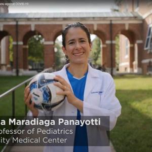 Dr. Maradiaga Panayotti in her white coat, outside holding a soccer ball