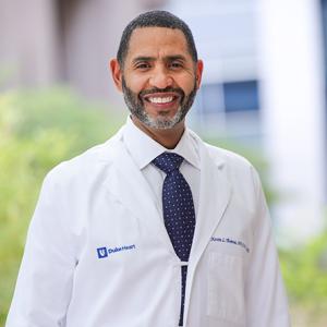 Black male physician in white coat standing outside