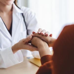Healthcare provider holding the hands of a patient across a table