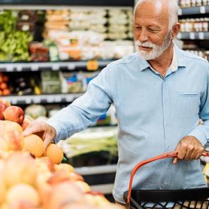 man with white beard and hair selecting produce at a grocery store