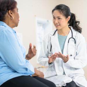 An Asian woman healthcare provider speaking with a Black woman patient.