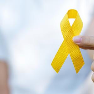 person holding a yellow suicide awareness ribbon