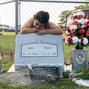 Young girl leaning on a gravestone mourning the deceased.