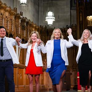 Four students with new white coats in Duke Chapel