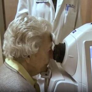 Elderly woman looking into an eye exam machine