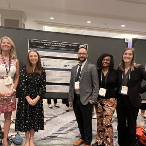 Five people in front of a conference poster