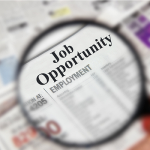 magnifying glass hovering over a newspaper that reads job opportunity
