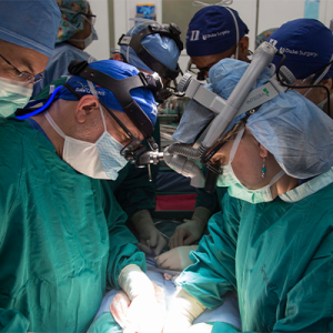 Dr. Sudan in an operating room performing surgery with other surgeons watching