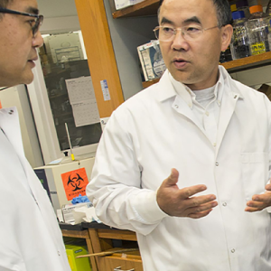 Zhou Pie, PhD speaking with a lab associate in his lab. 