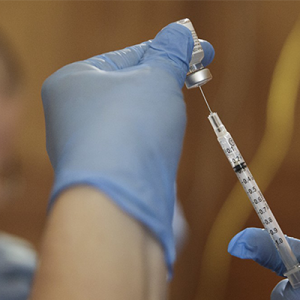 Gloved Hand drawing vaccine into a syringe