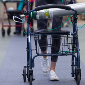legs of a person using a walker with an oxygen tank in the basket
