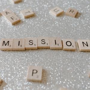 The word "mission" spelled out in Scrabble tiles on a sparkly background
