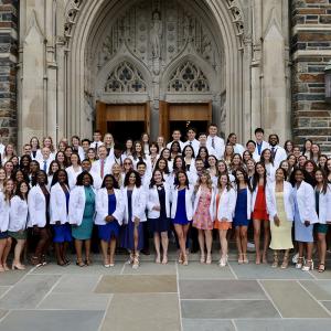 the Duke DPT class poses for a photo in front of Duke Chapel wearing their white coats