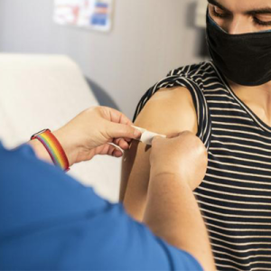 Young man receiving a having a bandage put on his upper arm.