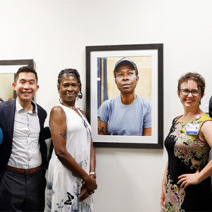 Butterfly Miles, center, poses near her portrait with the team during the opening of the Untold Stories Exhibition