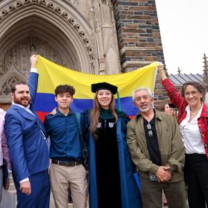 Karol in her graduatino cap and gown with her family after commencement, holding a Colombian flag