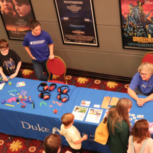 Duke faculty and staff greet children at a table with toys and other sensory-friendly items 