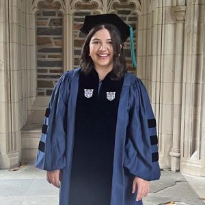 Caroline in her graduation cap and gown beside Duke Chapel