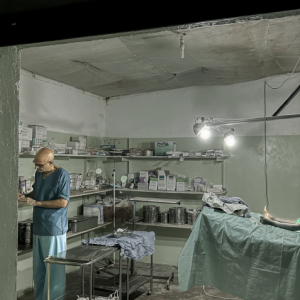 A man at preparing for work in a sparsely equipped operating room.