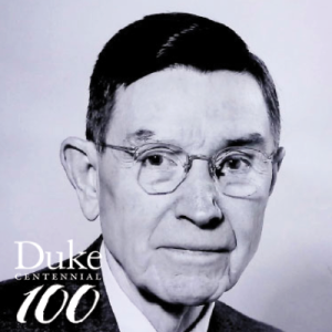A black and white portrait of an older man with dark hair wearing glasses.