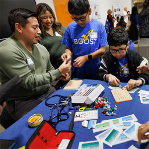 Duke med students Guissepe Yanez, MS3,  and Liban Mohamed, MS2, show BOOST students Gabriel Gil, 11, and Jonathan Sanchez, 11, how to suture during BOOST’s 20th anniversary celebration. 