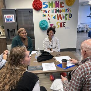 occupational therapy students and a client volunteer sitting at a table talking and smiling