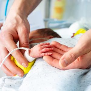 Closeup up adult's hands caring for an infant