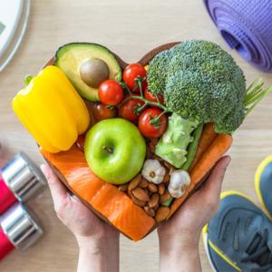 a heart shaped bowl of fruits, veggies, nuts, and salmon
