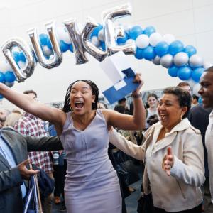 Excited student under Duke balloon banner