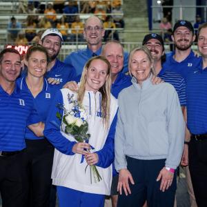 kyra posing with a group of people, holding a bouquet 