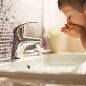 A child washing their face in running water