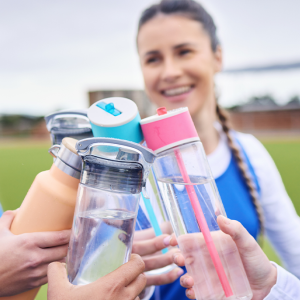 Three young teen girls toasting with their water bottles. 