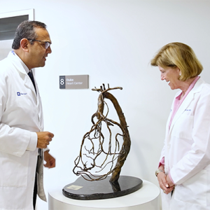 Manesh Patel, MD and Mary Klotman, MD looking at a small sculpture in a clinic hallway