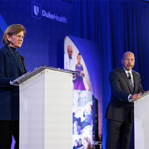 Mary Klotman, MD, and Craig Albanese, MD, MBA, standing behind podiums on stage. 