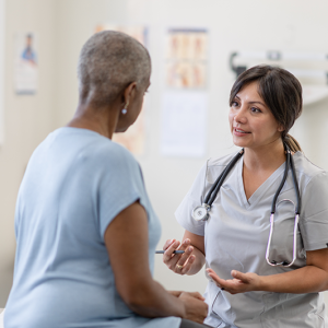 Healthcare provider speaking with a patient in an exam room. 