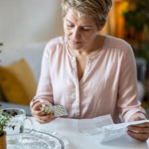 Woman sitting at a table looking at many bottles of pills