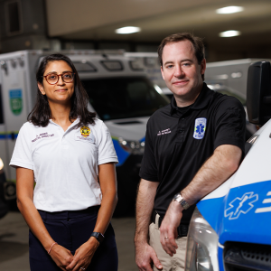  Andrew Godfrey, MD, and Anjni Joiner, DO, MPH in a garage surrounded by ambulances